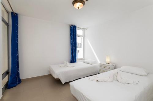 two beds in a white room with a window at TAC - Fisherman's Beach Apartment in Albufeira