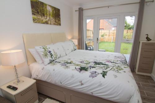 a bedroom with a bed and a lamp and a window at Little Birches in Grimston