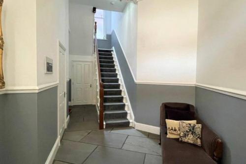a hallway with a staircase with a couch and a chair at CLITHEROE TOWN CENTRE MODERN 2 BED APARTMENT in Clitheroe