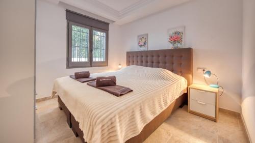 ein Schlafzimmer mit einem Bett mit einem braunen Kopfteil und einem Fenster in der Unterkunft Costacabana - Villa Davina in Lloret de Mar