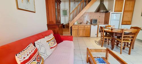 ein Wohnzimmer mit einem roten Sofa und einer Küche in der Unterkunft Petite maison de village au cœur du village in Saint-Clément-des-Baleines