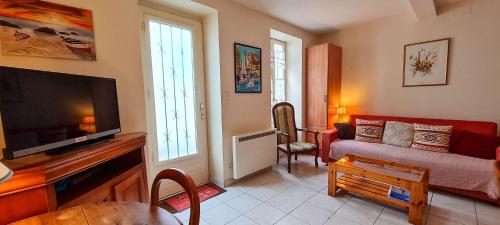 un salon avec un canapé et une télévision à écran plat dans l'établissement Petite maison de village au cœur du village, à Saint-Clément-des-Baleines
