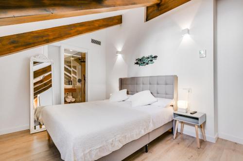 Habitación blanca con cama grande y techo de madera. en Palacio de Bobadilla Suites, en Cuenca