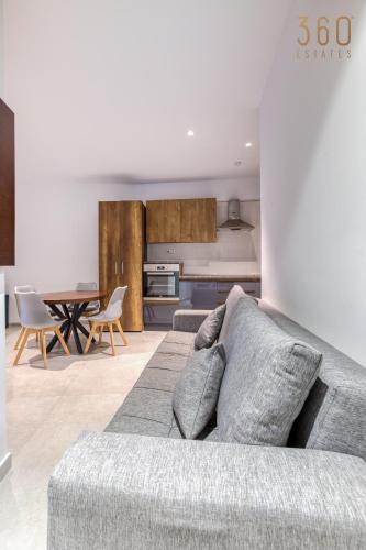 a living room with a couch and a kitchen at The Swieqi Poolside Suites in Is-Swieqi