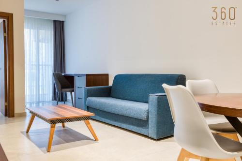a living room with a blue couch and a table at The Swieqi Poolside Suites in Is-Swieqi