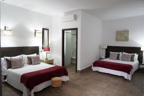 エル・ロシオにあるHospedarte Arenas de El Rocioのベッド2台と鏡が備わるホテルルームです。