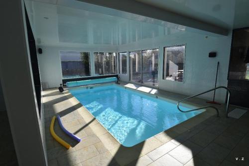 - une grande piscine dans une maison avec une grande fenêtre dans l'établissement La villa des amiets, piscine chauffée et à 500 m de la plage, à Cléder