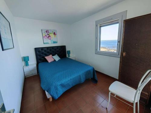 une chambre avec un lit avec une couverture bleue et une fenêtre dans l'établissement Superbe T3 avec piscine, plage à 30m, Cap d'Agde - FR-1-607-82, au Cap d'Agde