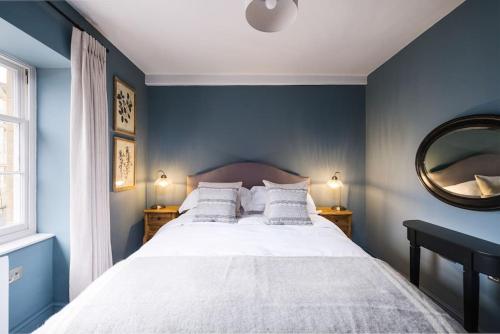 a bedroom with a bed with blue walls and a mirror at Great Escapes Oundle Flat 1 in Oundle