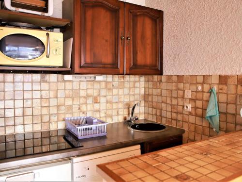 une cuisine avec un évier et un micro-ondes dans l'établissement Studio cabine au pied des pistes avec balcon et ascenseur à Auris en Oisans - FR-1-297-154, à Auris