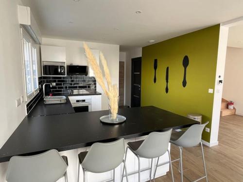 une cuisine avec un comptoir noir et des chaises blanches dans l'établissement Superbe Maison avec jardin, à Bezannes