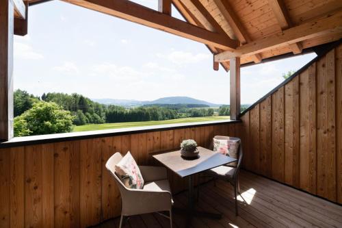 a room with a table and chairs on a deck with a view at Rosenhof Salzburger Seenland in Strasswalchen