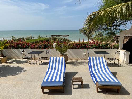 two blue and white chairs and tables and the ocean at Bine Bassile in Guéréo