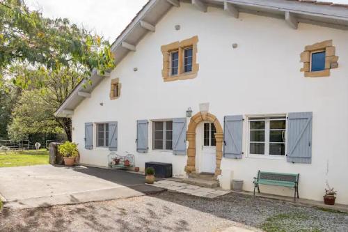 a white house with a bench in front of it at Les Ecuries du SEQUE in Saint-Martin-de-Seignanx