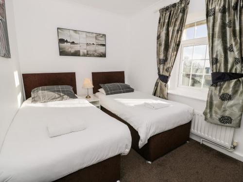two twin beds in a room with a window at Halcyon in Moelfre