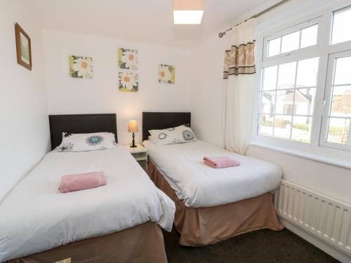 two twin beds in a room with a window at Halcyon in Moelfre