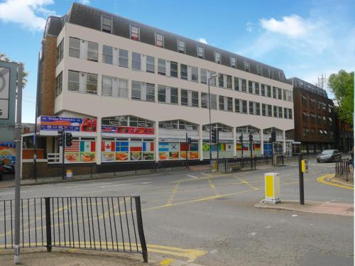 a large white building on the corner of a street at Kensal Green Backpackers in London