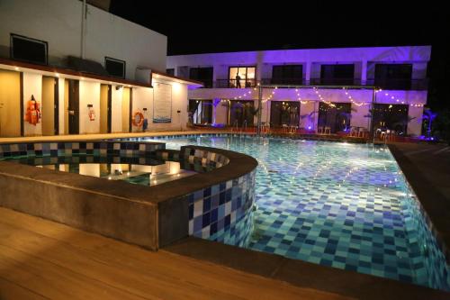 a swimming pool at night with purple lights at Suryaansh in Pālghar