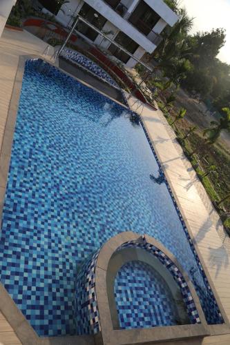 a large blue swimming pool with a building in the background at Suryaansh in Pālghar