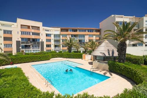 une piscine devant un immeuble dans l'établissement Appartement LE CAP D'AGDE Savannah beach 1,rez de jardin, accès piscine et plage. 4 PERSONNES, au Cap d'Agde