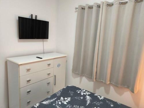 een slaapkamer met een bed en een dressoir met een tv bij Seu cantinho em Águas in Águas de Lindóia