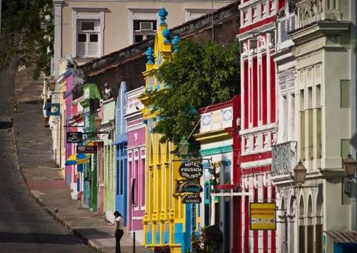 a person walking down a street with colorful buildings at Casa Carnaval Olinda in Olinda
