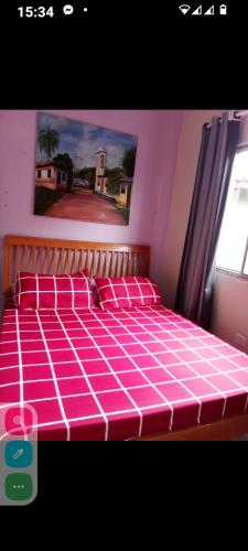 un letto rosa con cuscini rossi in una camera da letto di Juquehy casa para 6 pessoas com churrasqueira a São Sebastião