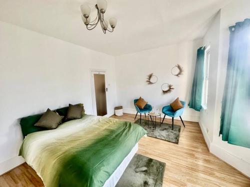 a bedroom with a large bed and two blue chairs at Cosy two bedroom apartment,SE13 in London