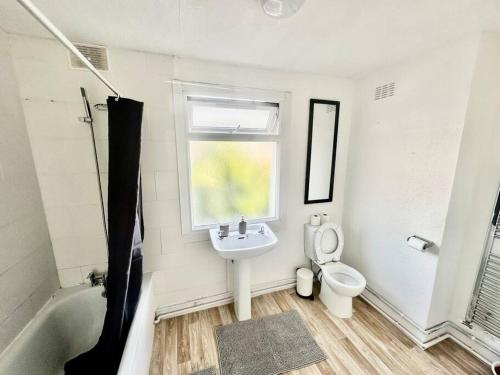 ein Bad mit einem Waschbecken, einem WC und einem Fenster in der Unterkunft Cosy two bedroom apartment,SE13 in London