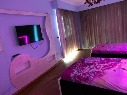 a purple room with two beds and a tv at Four seasons at san stefano in Alexandria