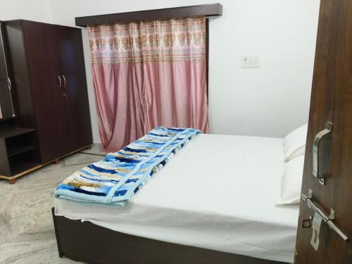 Pran Prasadam في Ayodhya: سرير أبيض في غرفة بها نافذة