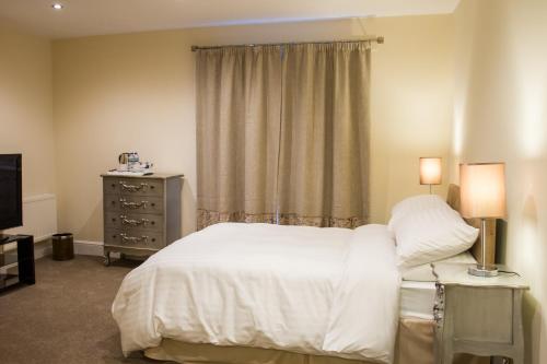 a bedroom with a bed and a dresser and a window at Fair Oak House Exeter Airport in Exeter