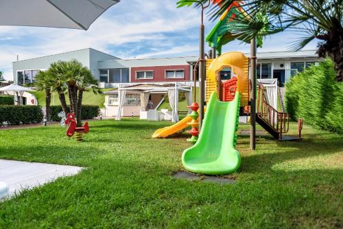 a playground with a slide in the grass at Domino Suite Hotel & Residence in Lido di Jesolo