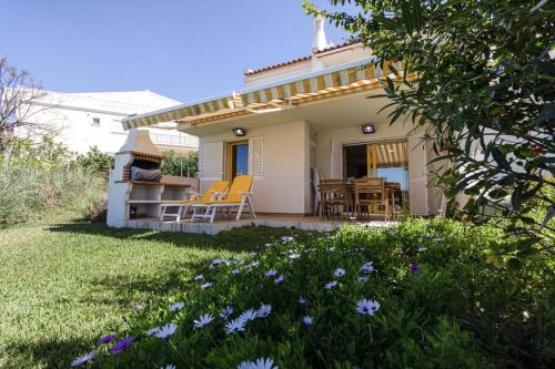 a small white house with yellow chairs on a patio at The Albufeira Concierge - Villa Pool & Tennis in Albufeira
