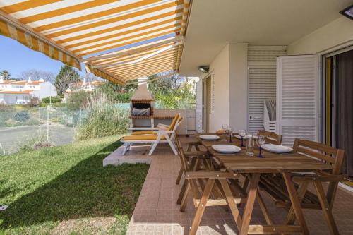 The Albufeira Concierge - Villa Pool & Tennis في Galé: فناء به طاولات وكراسي خشبية وشواية