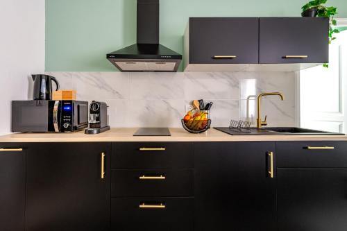 - une cuisine avec des placards noirs et un évier dans l'établissement Écrin de Verdure : Confort et Modernité, à Avignon