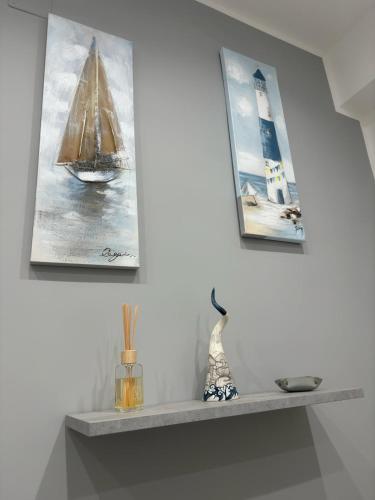 a shelf with three pictures of a sailboat and a lighthouse at Cliò guest house in Ercolano