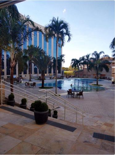 a resort with a pool with palm trees and a building at Condominio Barretos Thermas Park apto 312 in Barretos