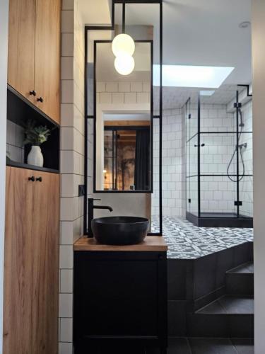 クラクフにあるCracovia Luxury Bright Apartment Great Location Saunaのバスルーム(黒い洗面台、鏡付)