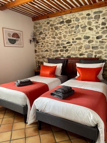 two beds in a room with a stone wall at Le Mas de Mirabel in Mirabel-aux-Baronnies
