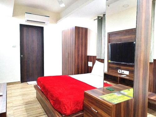 sypialnia z łóżkiem z czerwonym kocem i telewizorem w obiekcie Hotel comfort inn w mieście Calangute