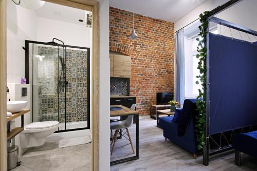 a bathroom with a brick wall and a toilet and a sink at Apartamenty Matejki in Gliwice