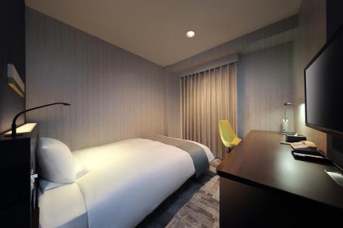 a hotel room with a white bed and a desk at JR-East Hotel Mets Fukushima in Fukushima