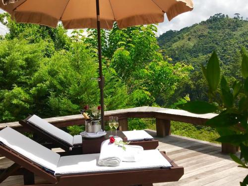 a table with an umbrella and chairs on a deck at Maua Brasil Hotelaria in Visconde De Maua