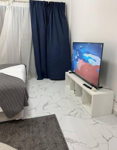 a living room with a tv on a white stand at Private room available in Arjan. in Dubai