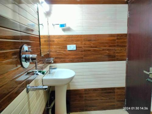 een badkamer met een witte wastafel en houten wanden bij Aurora Gangtok in Gangtok