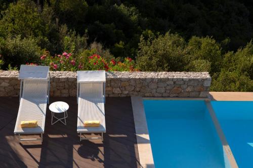 シヴォタにあるVilla Kastos - Stylish Luxury Villa with Direct Sea Accessの壁に隣接するプール(椅子2脚、テーブル付)
