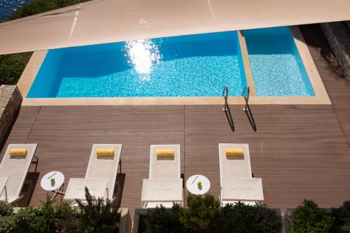 widok na basen z białymi krzesłami w obiekcie VILLAS MIRO - Luxury Villas with Direct Sea Access for 14 people w mieście Sivota