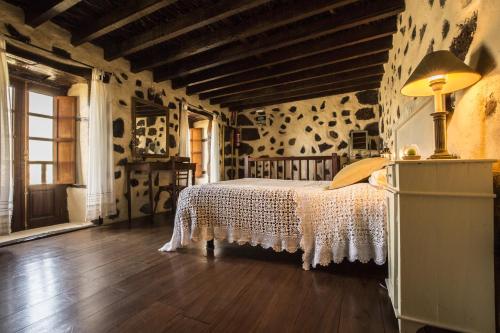 una camera con un letto in una stanza con pavimenti in legno di Casa Rural De Piedra a Frontera