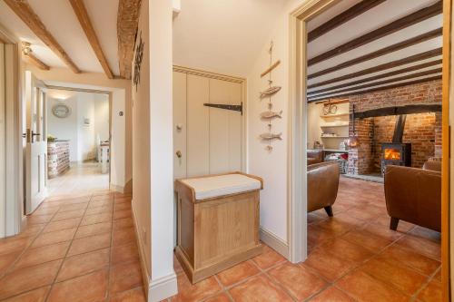 a hallway with a living room and a fireplace at Mayes Cottage in Brancaster